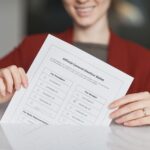 Smiling woman holds an election ballot paper during voting day.