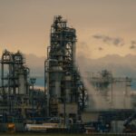 A detailed view of a refinery's towers against a cloudy dusk sky, showcasing industrial architecture.