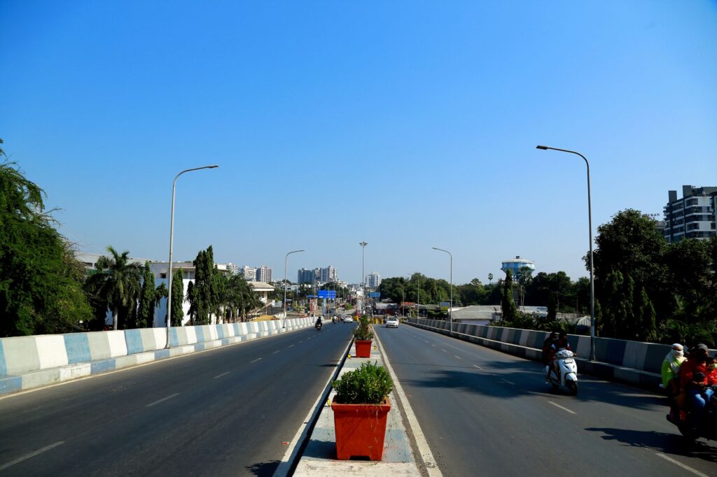An urban highway in Surat, India, showcasing city infrastructure and traffic under a clear blue sky.