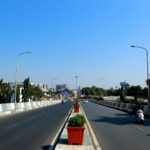 An urban highway in Surat, India, showcasing city infrastructure and traffic under a clear blue sky.