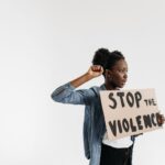 Black woman holding a 'Stop the Violence' sign in a peaceful protest setting.