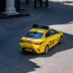 A yellow Uber taxi driving on a city street, shown from above.