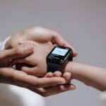 Close-up of an adult helping a child with a smartwatch, showcasing modern technology and parental guidance.