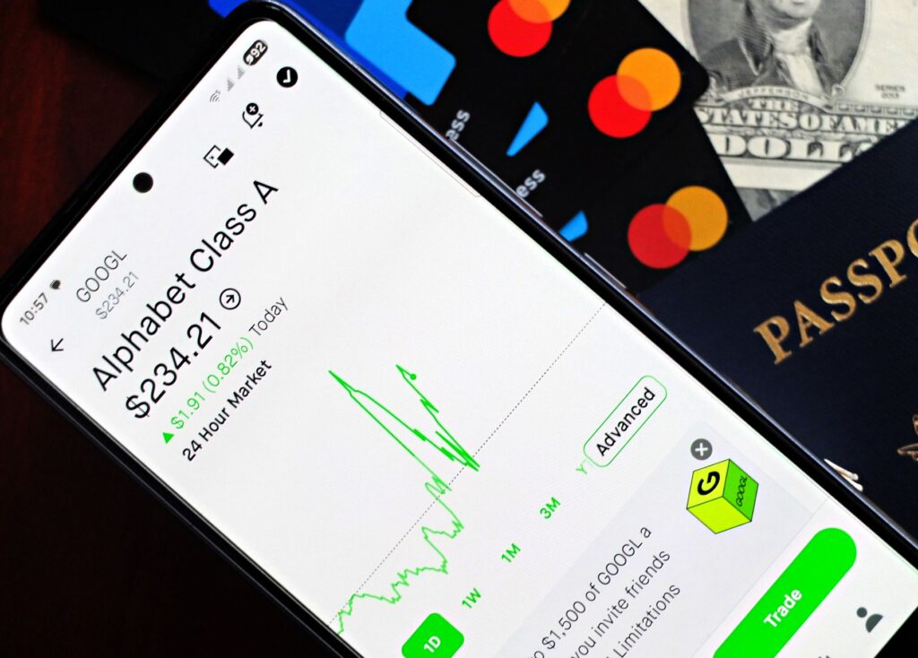 Smartphone displaying stock market app next to U.S. dollar and passport, representing global finance.