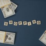 Stacked US dollars around shopping letters on a blue background.