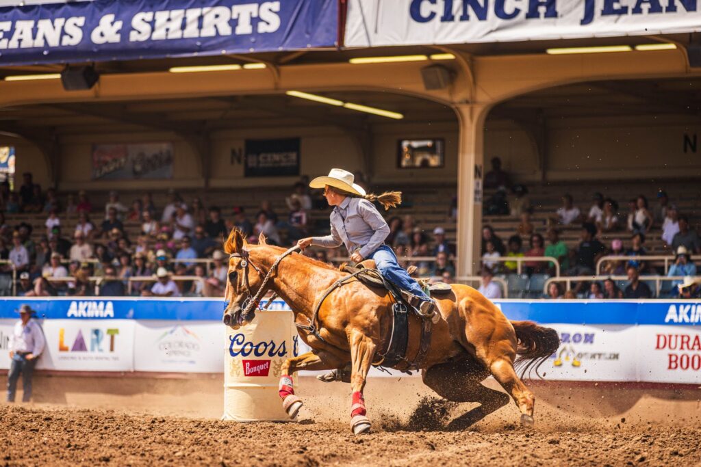 Action-packed barrel racing scene capturing a cowgirl and horse in perfect synchrony at a rodeo.
