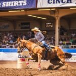Action-packed barrel racing scene capturing a cowgirl and horse in perfect synchrony at a rodeo.