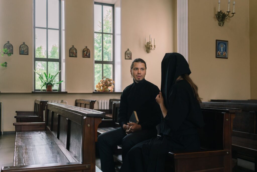A priest discussing with a parishioner in a peaceful church setting.