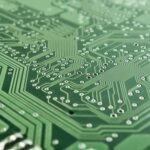 Detailed view of a green circuit board with complex patterns and pathways.