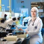 A female scientist in a laboratory setting, conducting research with microscopes and reference books.