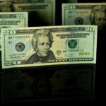 Detailed close-up of US twenty dollar bills displayed against a dark backdrop, showcasing American currency.
