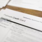 Close-up of a platinum credit card agreement document on a wooden desk.