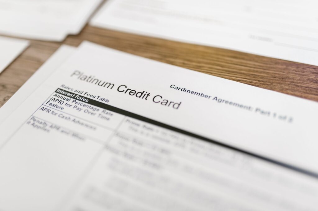 Close-up of a platinum credit card agreement document on a wooden desk.