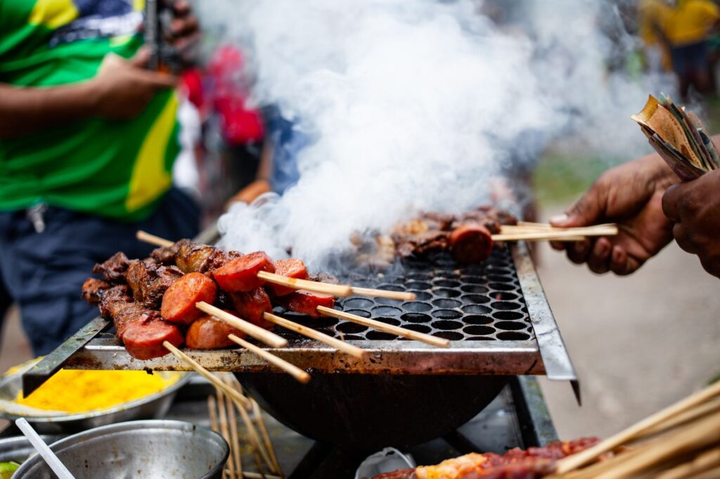 Juicy meat skewers grilling with smoke rising in Belém, Brazil street food scene.