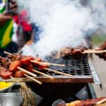 Juicy meat skewers grilling with smoke rising in Belém, Brazil street food scene.
