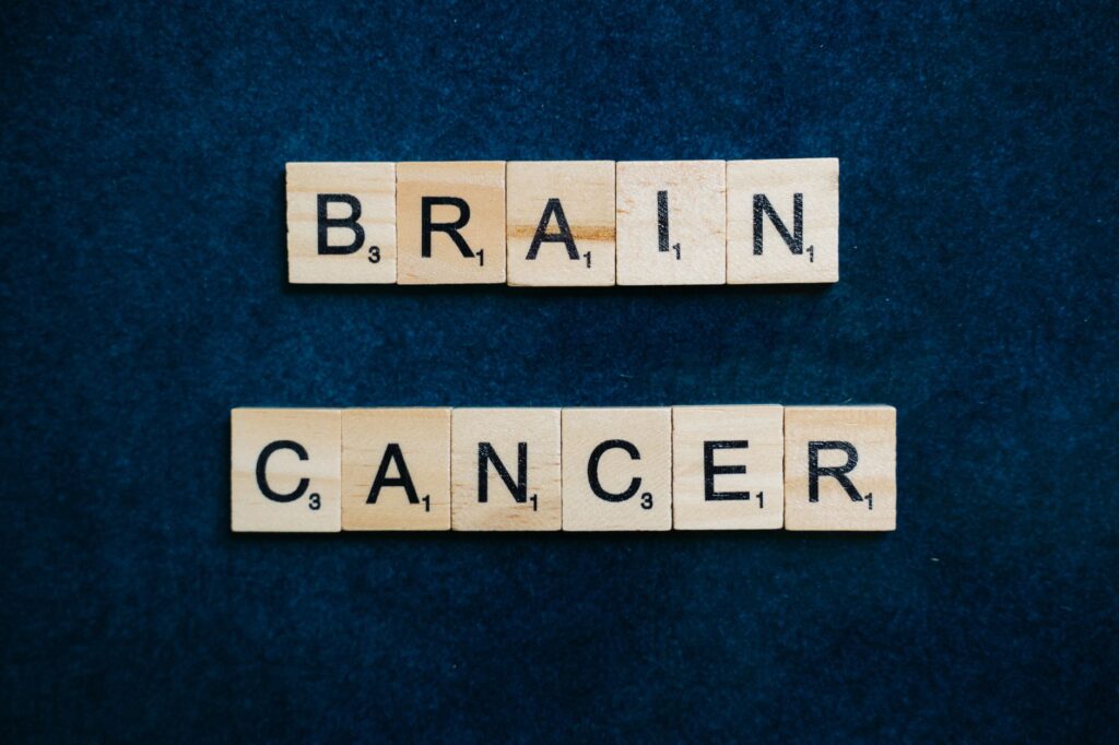 Wooden tiles spelling 'Brain Cancer' on a dark blue background, symbolizing awareness.