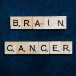 Wooden tiles spelling 'Brain Cancer' on a dark blue background, symbolizing awareness.