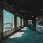 An urban industrial space under renovation with sunlight casting shadows through large windows.