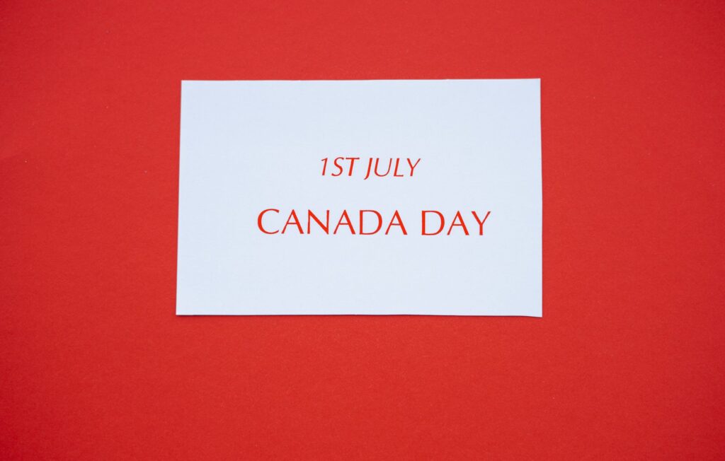 A white card with red text displaying '1st July Canada Day' on a red background.