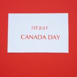 A white card with red text displaying '1st July Canada Day' on a red background.