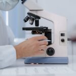 Researcher analyzing samples with a microscope in a lab setting.