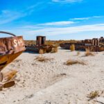 Abandoned rusty ships stranded on the dry Aral Sea bed in Uzbekistan, showcasing desertification.