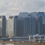 Cityscape featuring towering high-rise buildings against a mountainous backdrop.