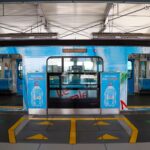 Modern metro station in Jakarta featuring a vibrant train with bold advertising graphics.