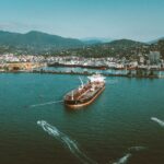 Stunning aerial view of a large ship in the port of Batumi, Georgia, surrounded by lush mountains.