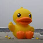 Large yellow inflatable duck at an outdoor event showcasing fun and creativity.