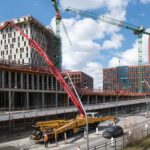 Busy construction site in Hamburg with cranes and trucks under a clear sky.