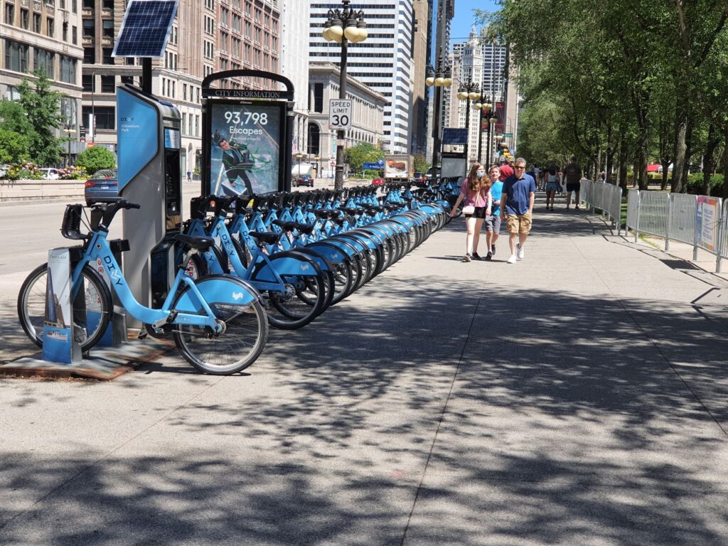 A bustling bike share station in downtown Chicago on a sunny day.