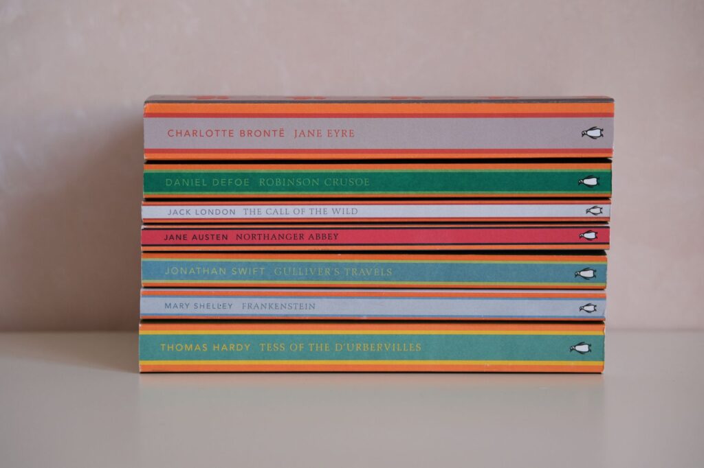 A neatly stacked collection of classic literature books on a plain background, perfect for bookworms.