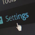 A close-up photo of a computer screen showing the settings button with a cursor hovering over it.