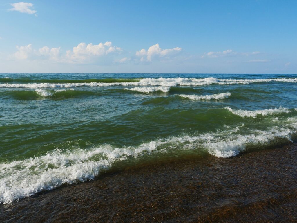 Serene beach waves on Lake Michigan's shore under a blue sky in Chesterton, Indiana.