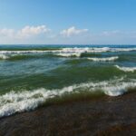 Serene beach waves on Lake Michigan's shore under a blue sky in Chesterton, Indiana.
