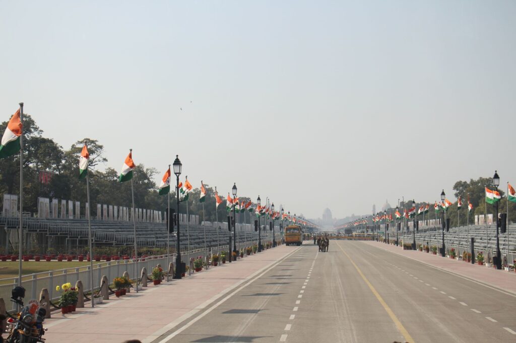Indian flags line Rajpath, Delhi, during Republic Day preparations. Clear sky, wide view.