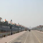 Indian flags line Rajpath, Delhi, during Republic Day preparations. Clear sky, wide view.
