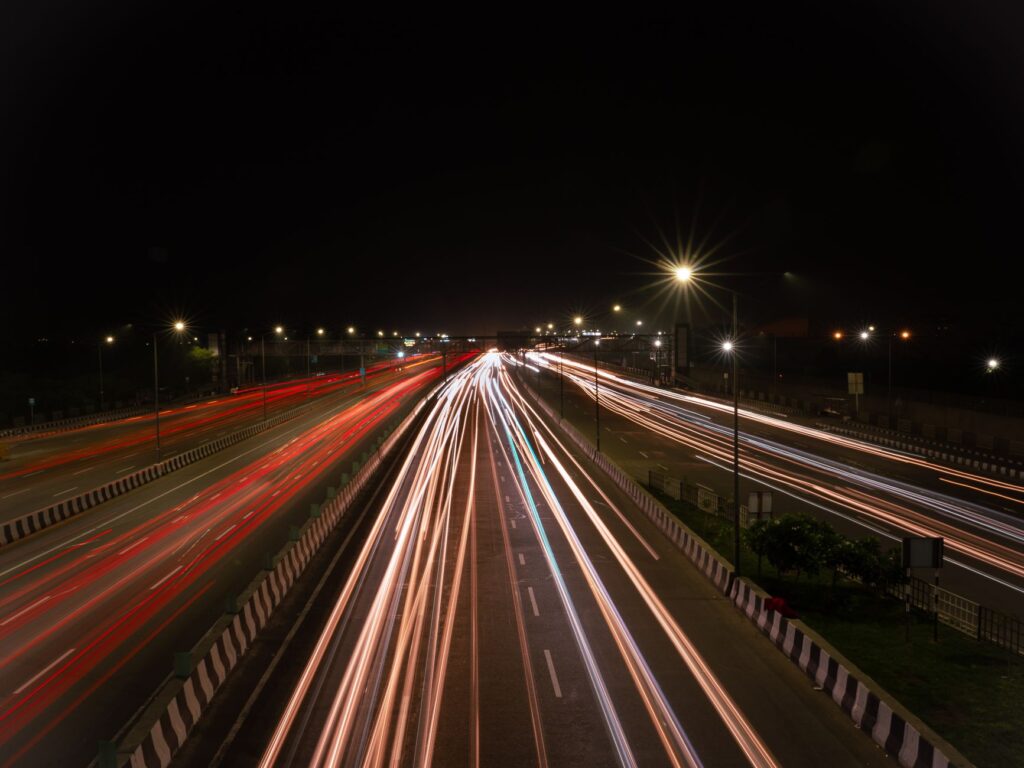 Long exposure shot capturing dynamic city traffic on Delhi highway at night.