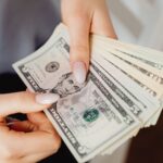 Hands count US dollar bills, showcasing finance and cash handling concepts.