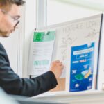 Real estate agent analyzing mortgage loan details on a whiteboard in an office setting.
