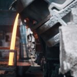 A powerful image of molten metal pouring in a heavy industry steel mill setting.