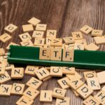 Wooden tiles spelling ETF on a game holder, representing investment themes.