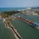 Aerial shot of Imbituba port showing docks, cranes, and coastline in Brazil.