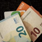 Close-up of euro banknotes and credit cards on a dark textured surface.