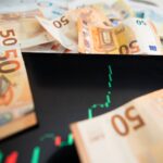 Close-up of 50 euro banknotes with a digital stock market chart on a tablet, depicting financial growth.