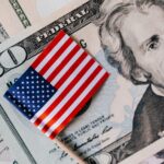 From above of small American flag placed on stack of 20 dollar bills as national currency for business financial operations