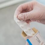 Close-up of a hand in gloves holding a blister pack of pills, symbolizing medical care.