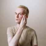 Portrait of a young man using a skincare product for a fresh and hydrated face indoors.
