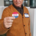 A senior adult holding a vote sticker inside a polling booth during election day.